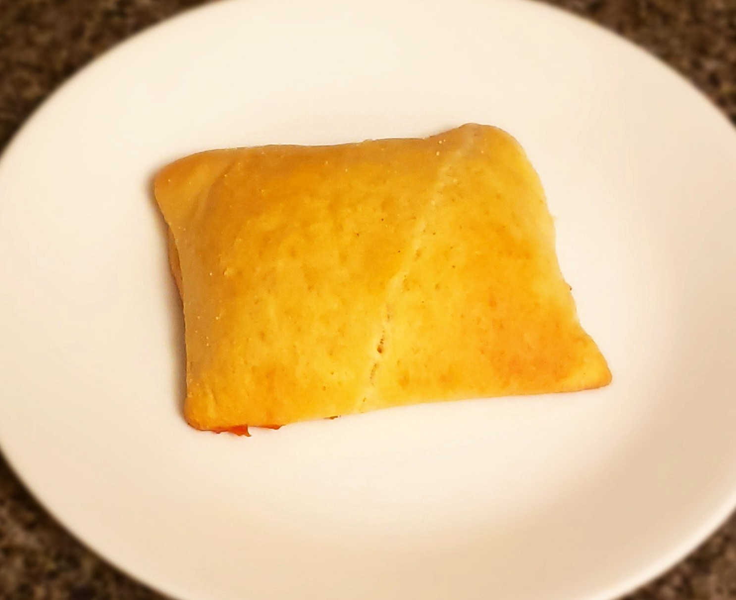A square piece of golden brown baked pastry dough on a while plate