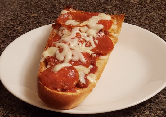 A slice of French Bread Pizza on a white plate