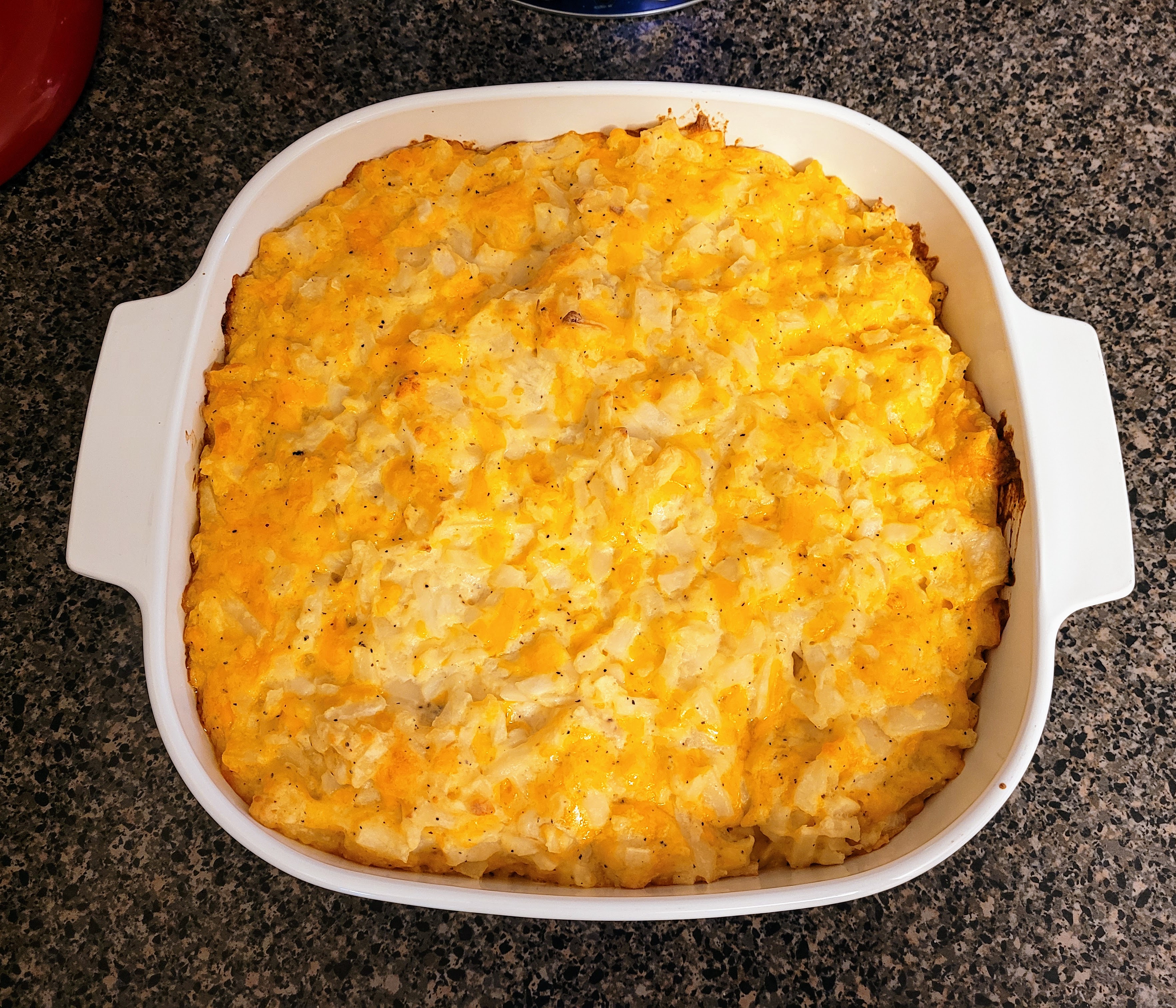 Casserole dish with hashbrown casserole, golden on top and browned a bit on the edges